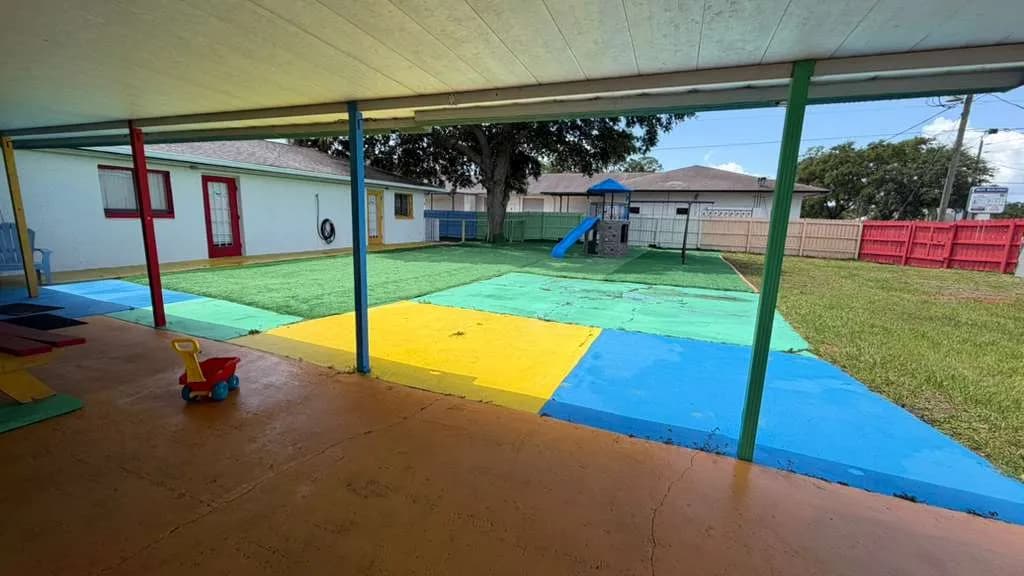 Covered outdoor play patio with colorful flooring at A Magic World Child Care Center in Palm Bay, FL