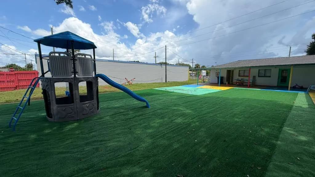 Children's climbing tower and slide on artificial turf playground at A Magic World Child Care Center