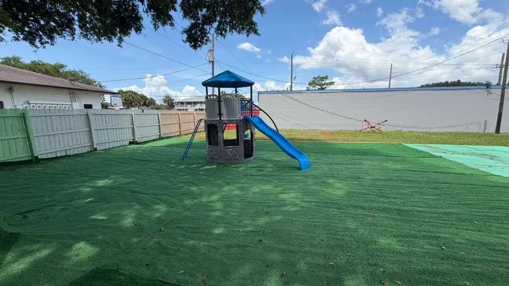 Fenced backyard playground with climbing structure at A Magic World Child Care Center