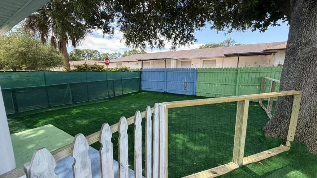 Secure fenced toddler play yard with shade tree at A Magic World Child Care Center in Palm Bay, FL